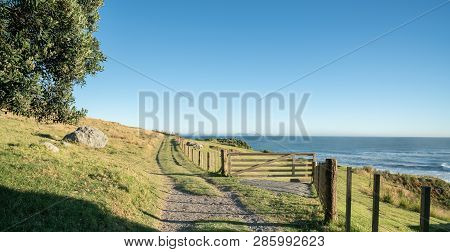 Track Along Fenceline Past Closed Farm Gate On Slpoing Hillside With View Out To Sea And Horizon.