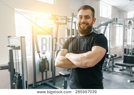 Portrait Of Smiling Personal Fitness Trainer In Gym, Confident Man With Folded Hands Looking At Came