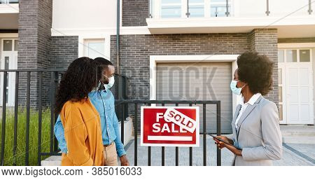 African American Young Happy Couple In Medical Masks Buying House At Outskirt And Talking With Femal