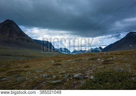 Hiking in Swedish Lapland. Man trekking alone in northern Sweden in Stuor Reaiddavaggi valley. Arctic mountain nature of Scandinavia in summer cloudy day