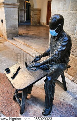Elche, Alicante, Spain- September 9, 2020: Sculpture Of A Shoemaker Worker Covered With A Mask In Th