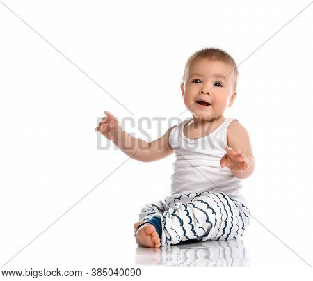 Little Boy Sits In A White Studio On The Floor, Wearing A Gray T-shirt With A Star