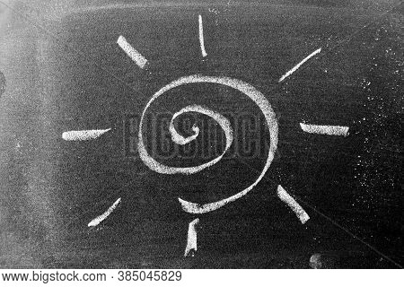 White Color Chalk Hand Drawing In Sprial Sun With Ray Shape On Blackboard Background
