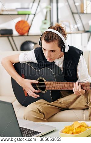 Teenge Boy In Headphones Following Chords On Laptop Screen When Learning New Song