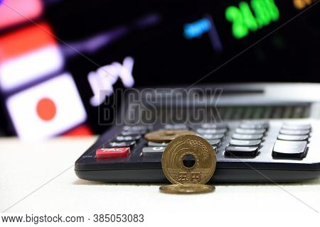 Japanese Five Yen Coins (jpy) On White Floor With Black Calculator And Digital Board Of Currency Exc
