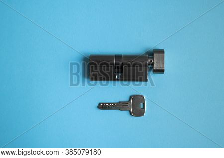 A Door Lock Cylinder Core With Key On The Blue Background. The Cylinder Of The Lock With Key. Instal
