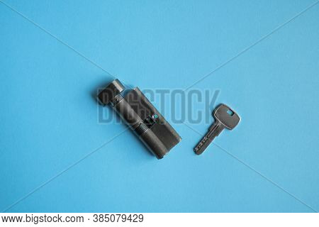 A Door Lock Cylinder Core With Key On The Blue Background. The Cylinder Of The Lock With Key. Instal
