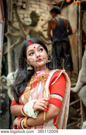 Portrait Of Beautiful Indian Girl Standing In Front Of Durga Idol Wearing Traditional Indian Saree, 