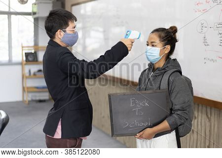 Teacher is taking a student's or college student's body temperature to measure the body of someone w