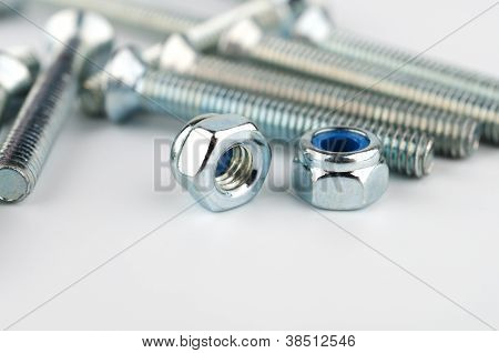 Two metal nuts on a background of metal bolts