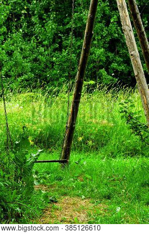 Old Wooden Rustic Garden Iron Chain Hanging Swing On Green Grass Background. Selective Soft Focus. T