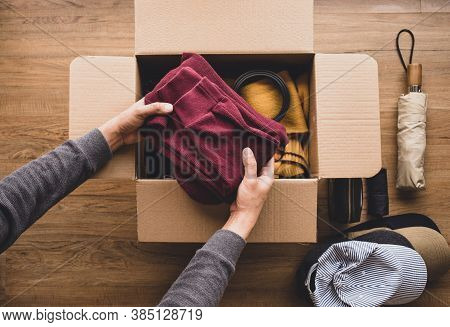 Cleaning Home And Donation Concepts With Young Person Putting Accessories Clothing In Brown Box.givi