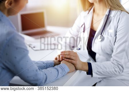 Unknown Woman-doctor Is Holding Her Patients Hands, Discussing Current Health Examination, While The