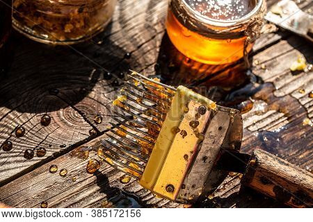 Jar Of Fresh Honey In A Glass Jar, Beekeeping Tools Outside. Frame With Bees Wax Structure Full Of F