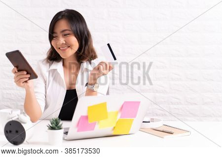 Happy Woman Use Smart Phone And Credit Card At Office