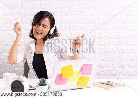Happy Woman With Headphones Listening Music At Office