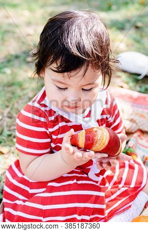 Cute Little Baby In A Red Dress And Srtaw Hat On A Picnic In The Park