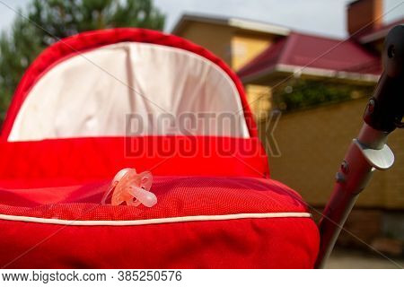 The Pink Nipple For The Baby Lies On The Baby Carriage. Baby's Asleep. Background.