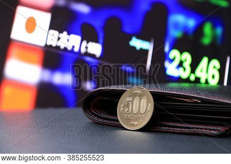 Japanese Five Hundred Yen Coins On Reverse (jpy) On Black Floor With Black Wallet And Digital Board 