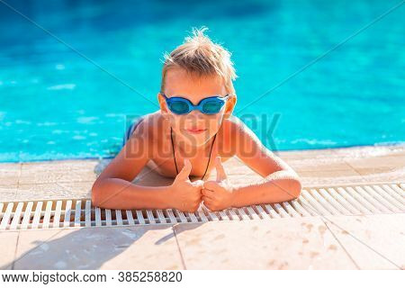 Cute Happy Little Boy In Goggles Swimming In The Swimming Pool