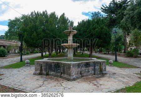 Ancient Stone Fountain Surrounded By Nature, Located At The Entrance Of The Monastery Of Lluc, Islan