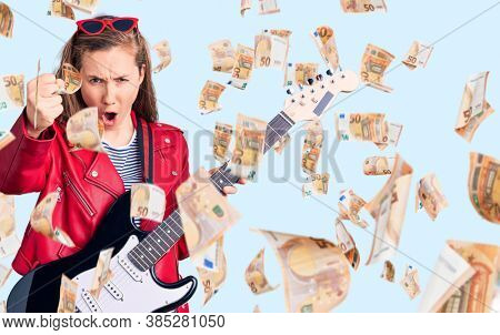 Young beautiful blonde woman playing electric guitar annoyed and frustrated shouting with anger, yelling crazy with anger and hand raised