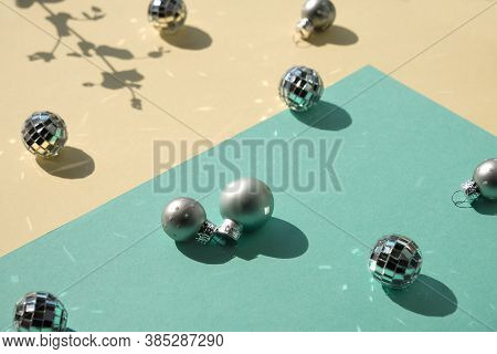 Mirror Balls And Silver Xmas Baubles On Mint Green And Yellow Layered Paper. Geometric Christmas Bac