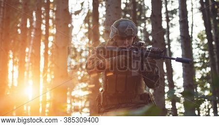 modern warfare soldier in action aiming at weapon  laser sight optics  in combat position while searching for a target in battle