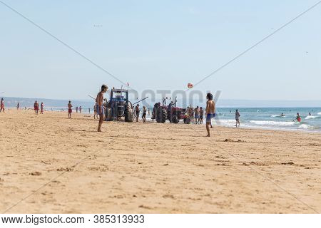 Costa Da Caparica, Portugal - September 10, 2020: An Artel Of Fishermen Trawls Fish From The Tourist