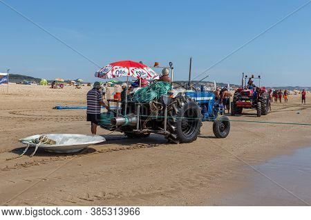 Costa Da Caparica, Portugal - September 10, 2020: An Artel Of Fishermen Trawls Fish From The Tourist