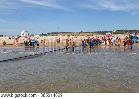Costa Da Caparica, Portugal - September 10, 2020: An Artel Of Fishermen Trawls Fish From The Tourist