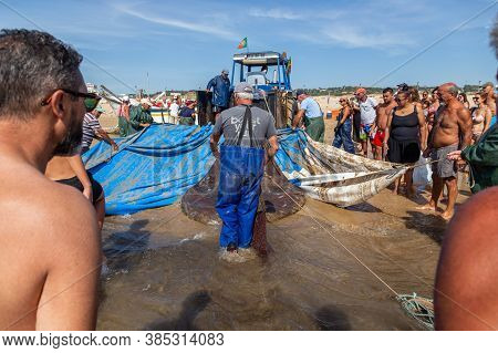 Costa Da Caparica, Portugal - September 10, 2020: An Artel Of Fishermen Trawls Fish From The Tourist