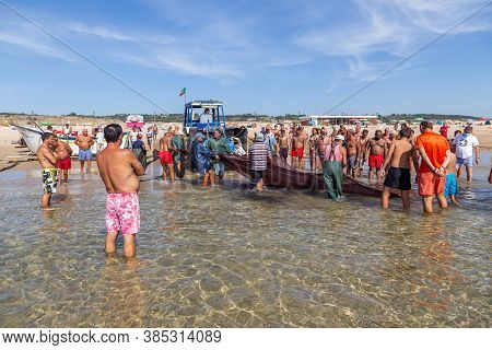 Costa Da Caparica, Portugal - September 10, 2020: An Artel Of Fishermen Trawls Fish From The Tourist
