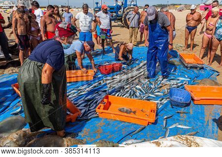 Costa Da Caparica, Portugal - September 10, 2020: An Artel Of Fishermen Trawls Fish From The Tourist