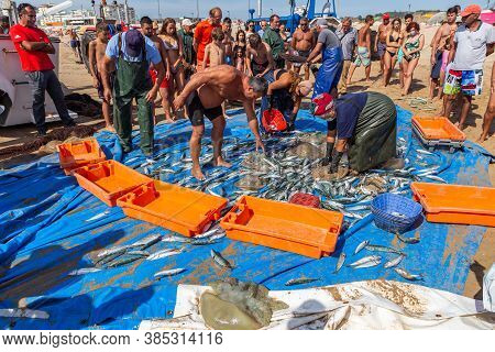 Costa Da Caparica, Portugal - September 10, 2020: An Artel Of Fishermen Trawls Fish From The Tourist