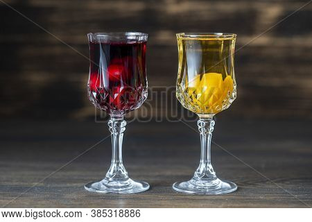 Homemade Tincture Of Red Cherry And Yellow Cherry Plum In A Wine Crystal Glasses On Wooden Backgroun