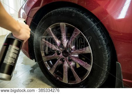 Service Worker Washing Car Wheell At A Car Wash.