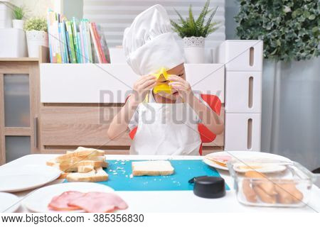 Cute Asian Boy Wearing Chef Hat And Apron Having Fun Preparing Sandwiches, Little Kid Making Cookie 