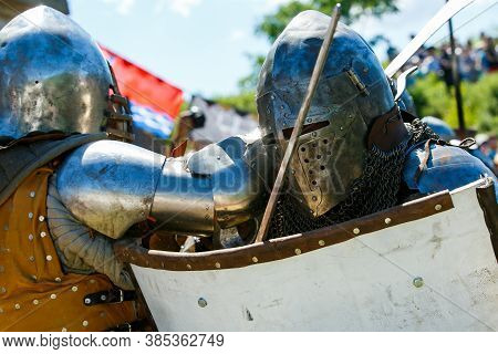 Knight Tournament. Medieval Restorers Fight With Swords In Armor At A Knightly Tournament