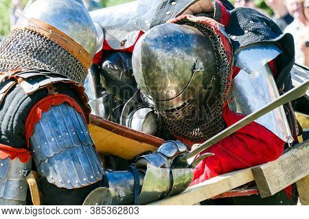 Knight Tournament. Medieval Restorers Fight With Swords In Armor At A Knightly Tournament