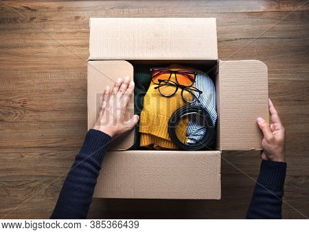 Donation Concepts With Young Person Packing Accessories Clothing In Brown Box.giving And Sharing Wit