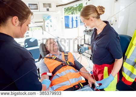 Emergency doctor in ambulance talking to injured man looking cheerful considering the circumstances