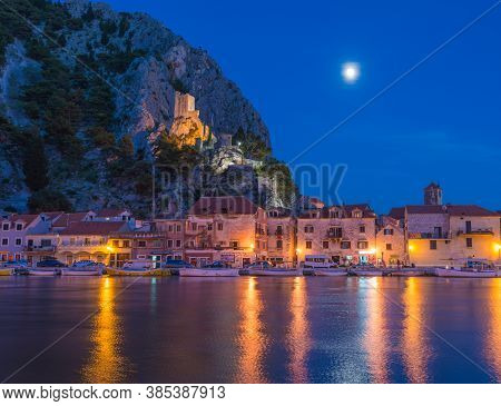 Night View Of A Tower Mirabella With The Moon And Reflection. Omis, Croatia, Europe.