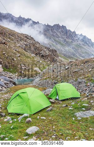 Two Green Tents Near Lake And Clouds Over In Mountains. Kyrgyz Alatoo Mountains.