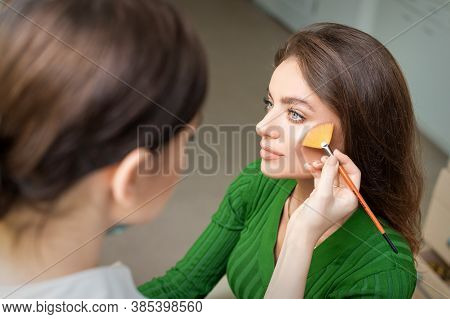 Make Up Artist Applying Professional Make Up Of Tonal Foundation On The Face Of Beautiful Young Cauc