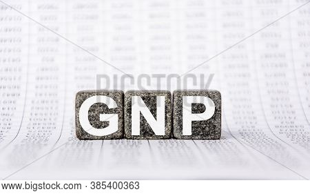 Three Stone Cubes On The Background Of White Financial Statements, Tables With The Word Gnp. Strong 