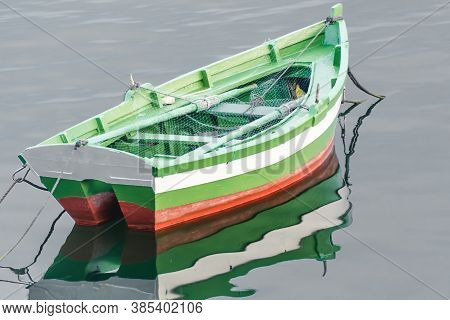 Small Fishing Boat Reflected In A Calm Sea