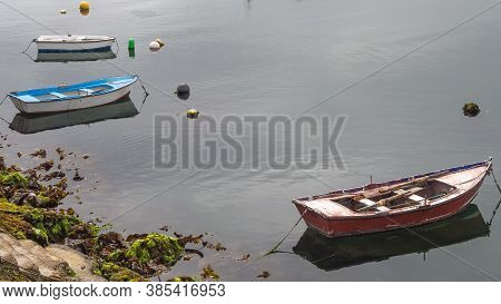 Three Small Fishing Boats Moored In A Calm Sea