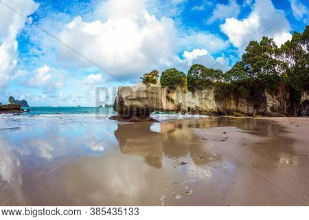 Cathedral Cave on the North Island of New Zealand. Coromandel Peninsula. Bizarre clouds and coastal cliffs reflected in the tidal waters of the Pacific Ocean. The concept of ecological, photo tourism
