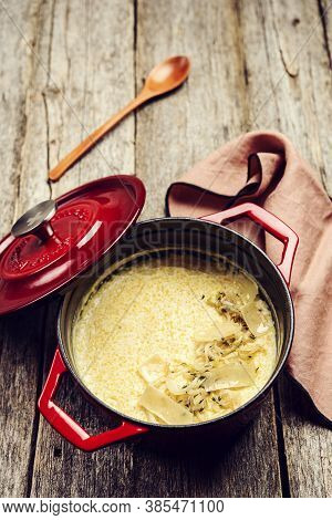 Creamy Polenta With Baked Onion And Cheese In Cast Iron Pot On Rustic Wooden Background. Italian Foo